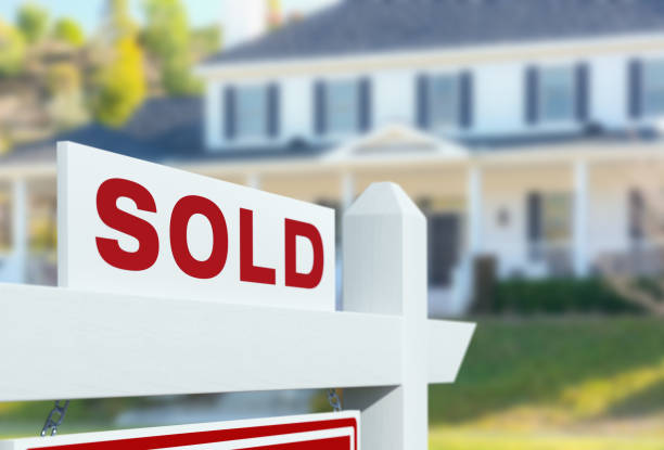 A SOLD real estate sign in front of a large white house